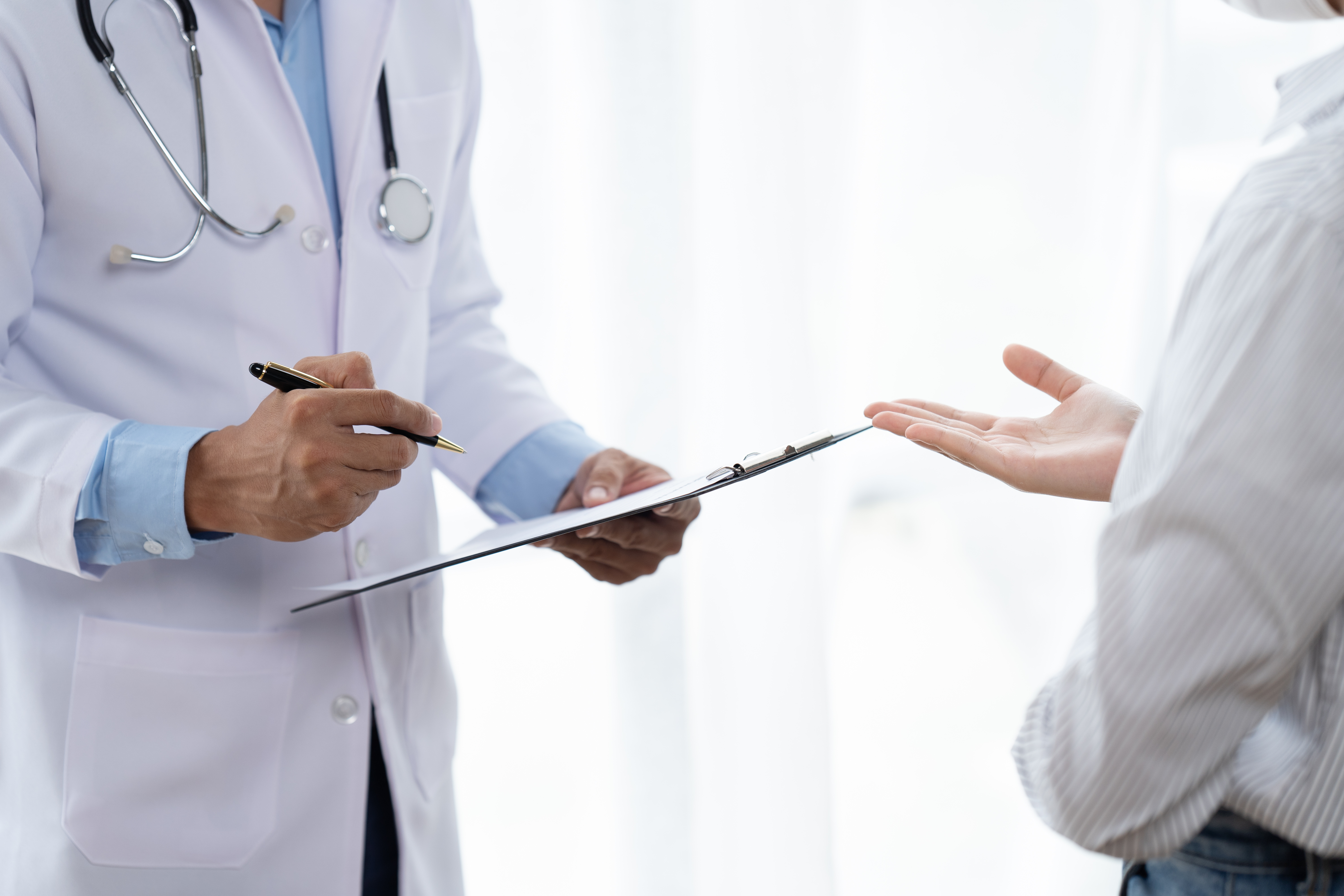 Doctor and patient sitting and talking at medical examination at hospital